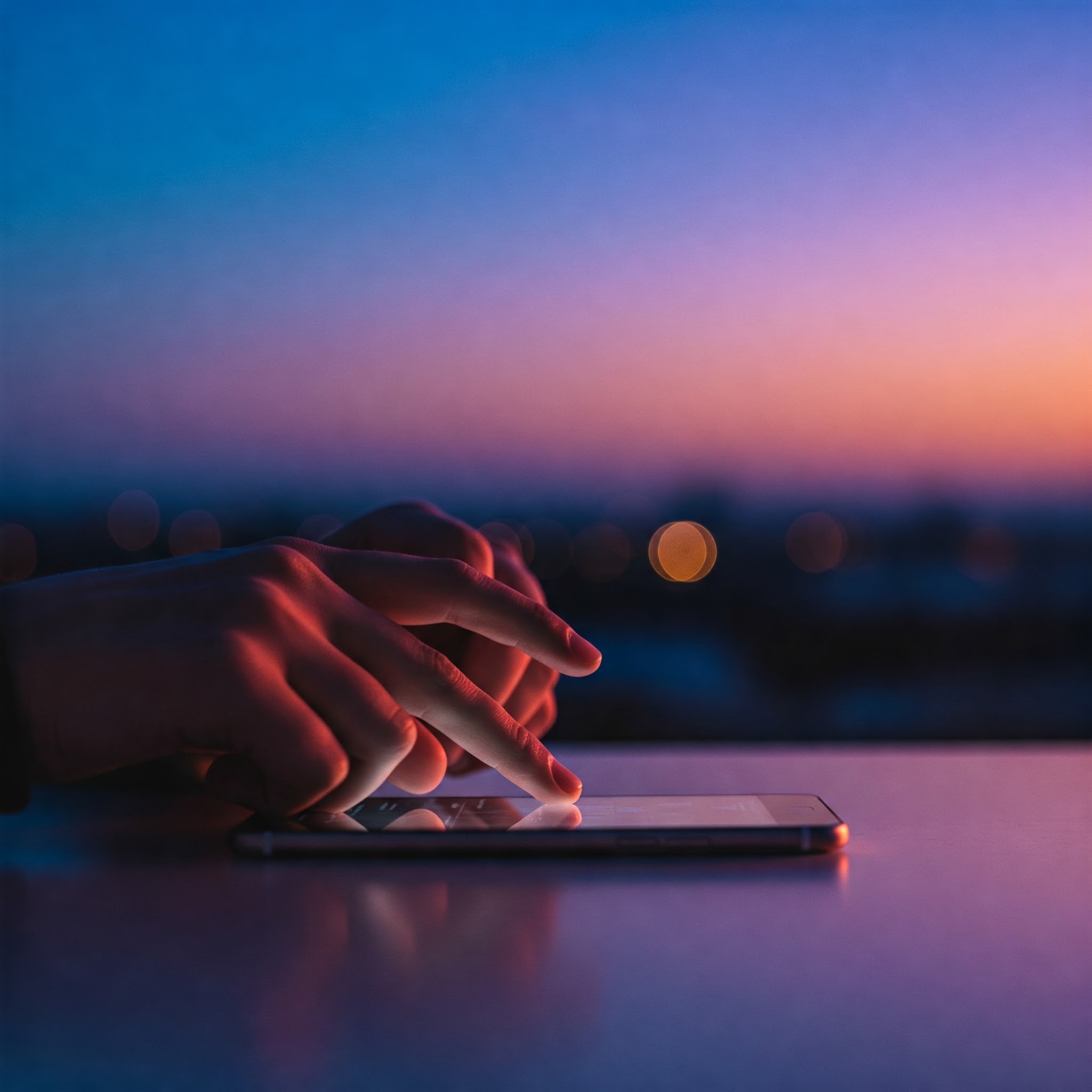 photo of Hands using a Cell Phone at Sunset
